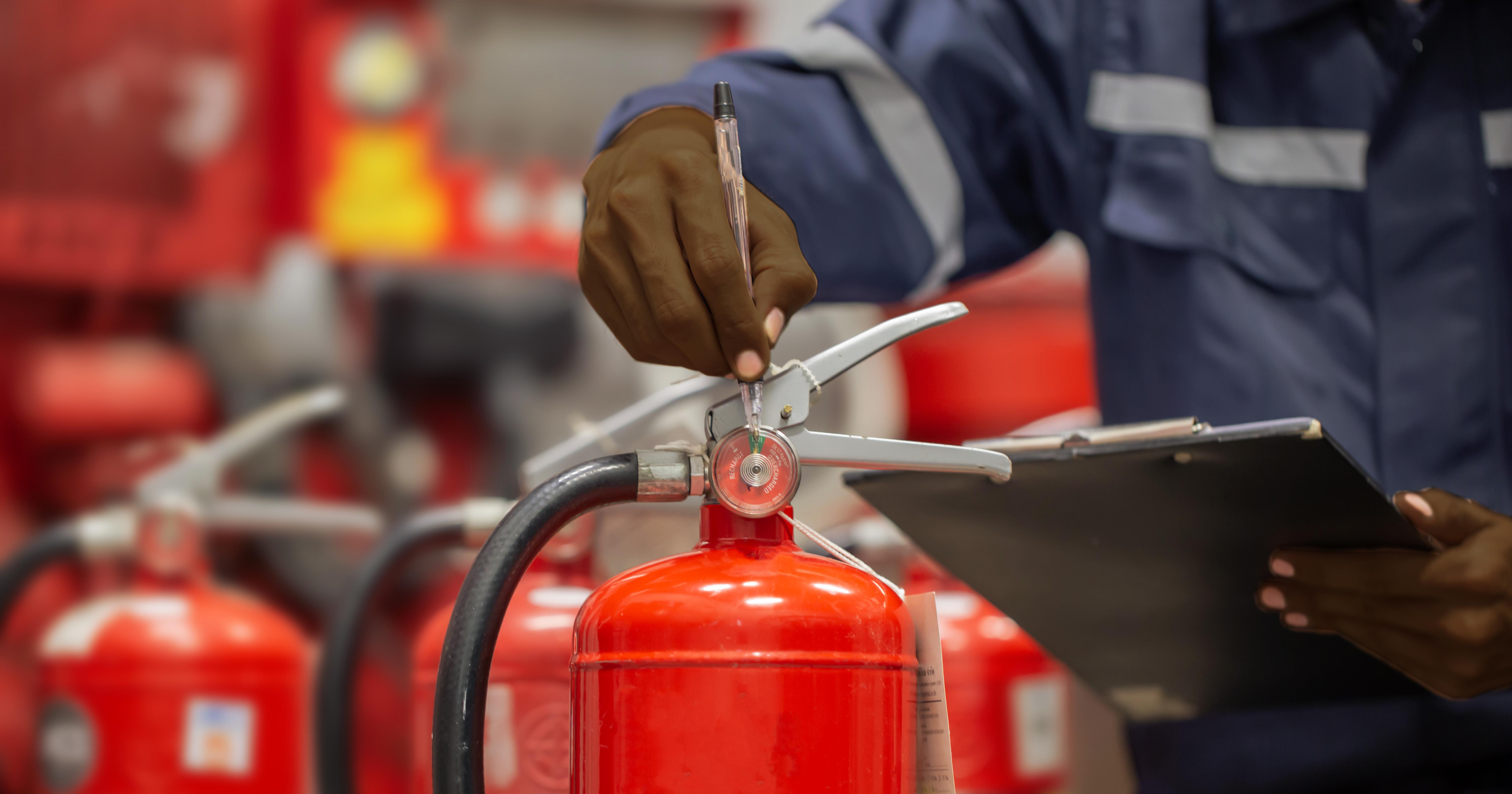 Employé Apave inspecte un extincteur