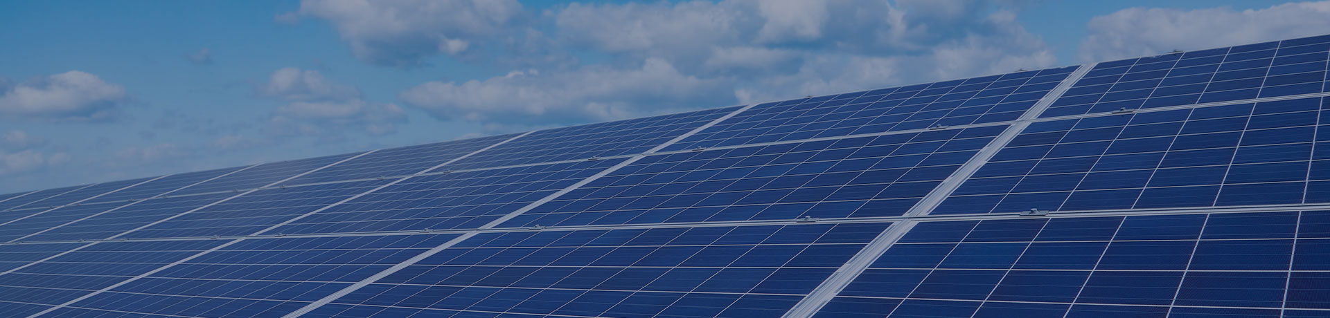 Des panneaux solaires en premier plan et le ciel bleu avec nuages en arrière plan